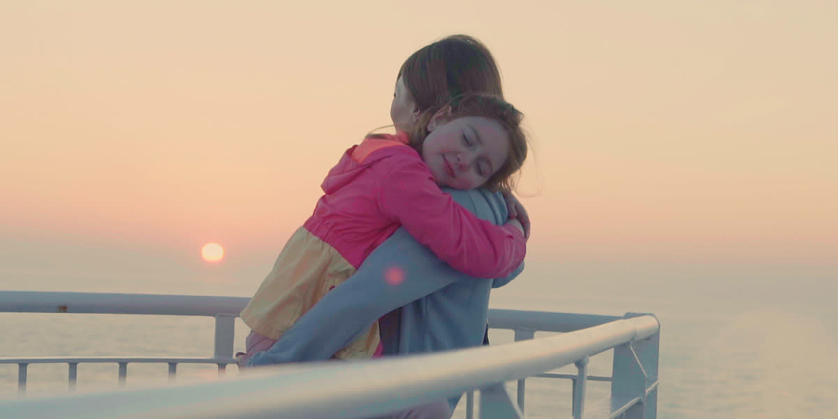 Child hugging mother on deck Promo