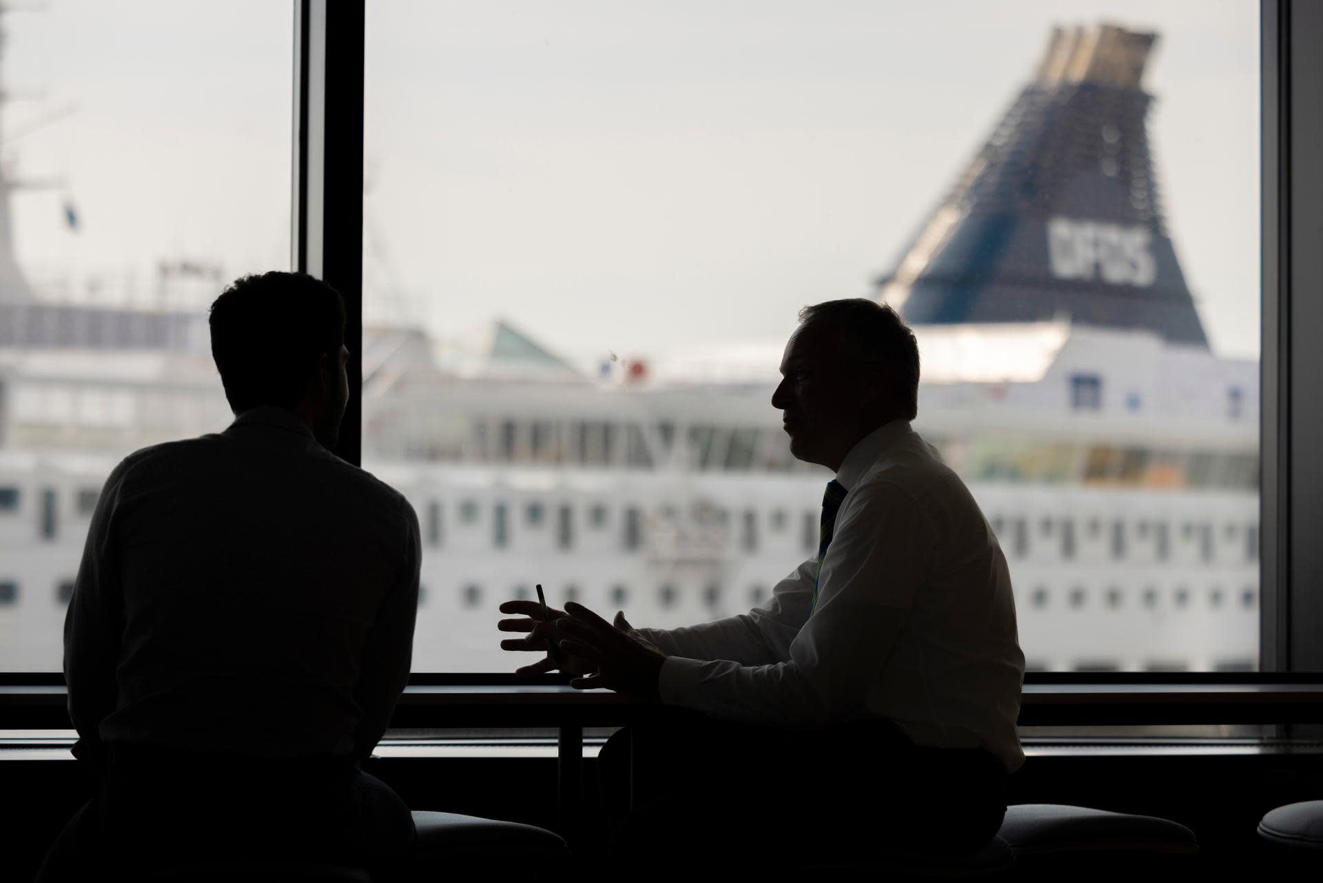 Two persons speaking together, in an office environment, with in the background a DFDS vessel in the harbour 2H0A0794 about section whistleblower system