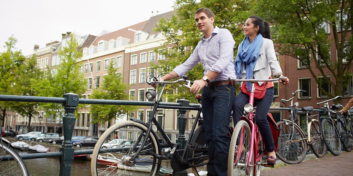 Couple on bicycles in Amsterdam on the canal Bicycle around Amsterdam
