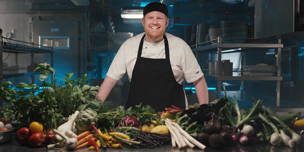 Smilende chef i Explores køkken med friske grønsager Explorer Smiling chef with greens